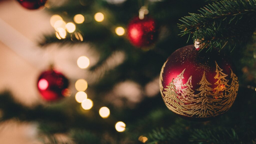 Große Christbaumkugel, Weihnachtsbaum verschwommen im Hintergrund