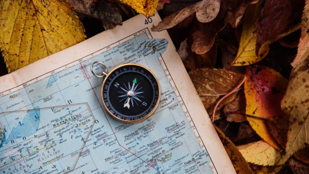 Karte mit Kompass drauf zu sehen, liegt im Freien auf herbstlichen Blättern