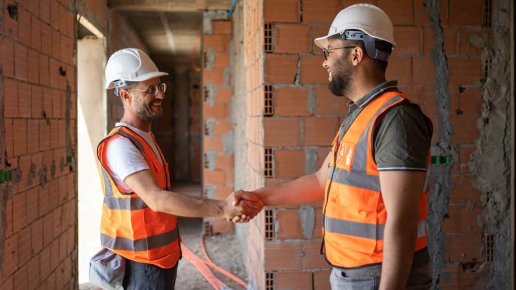 Zwei Bauarbeiter in Warnwesten auf der Baustelle Begrüßen sich