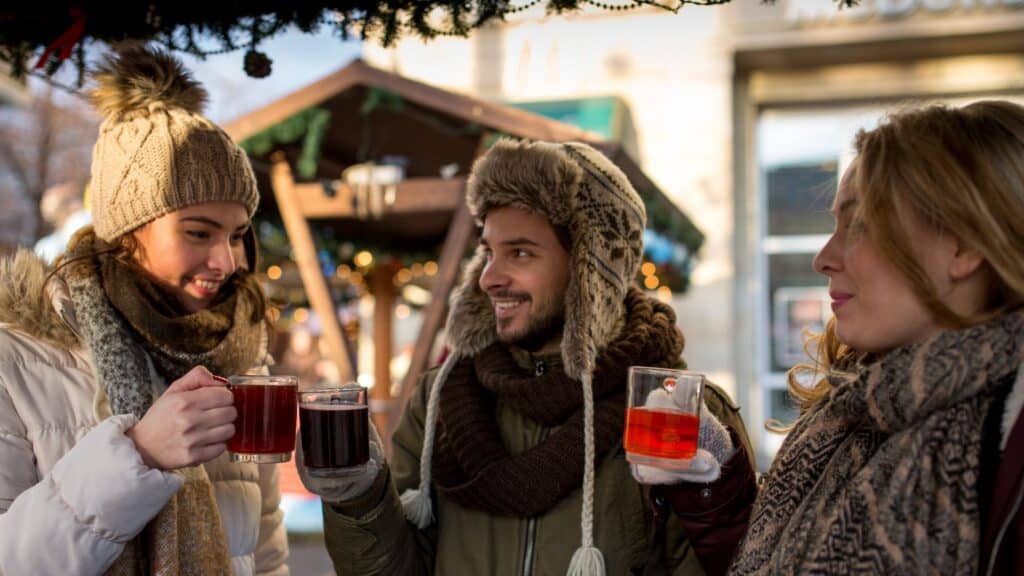 3 Kollegen trinken Glühwein auf einem Weihnachtsmarkt