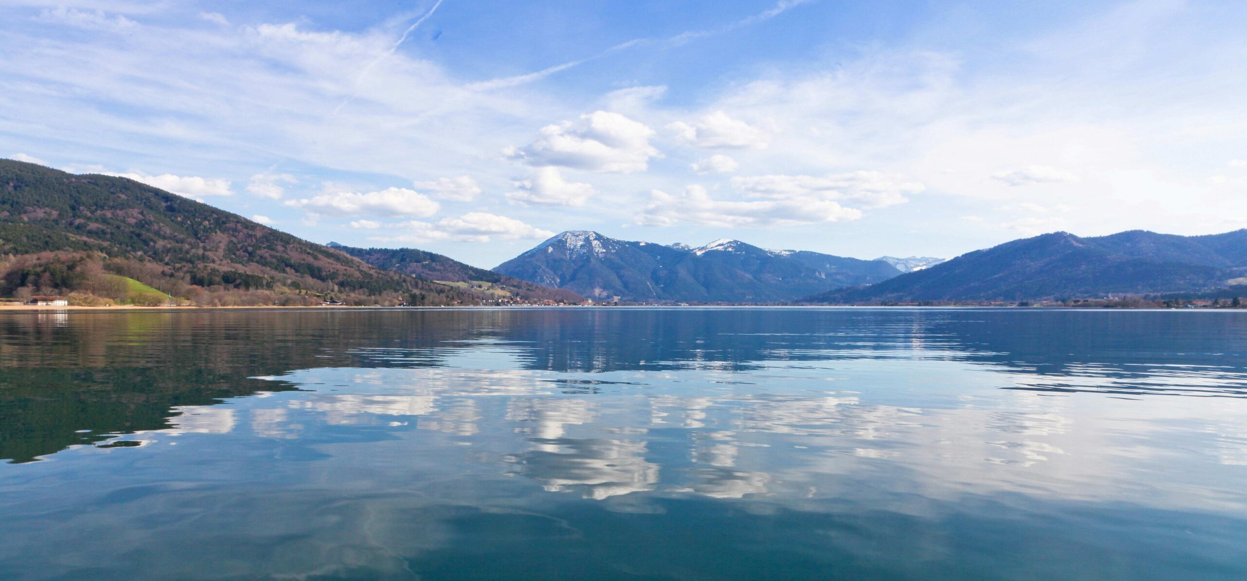 Blick auf den Tegernsee mit Bergen und Spiegelung der Wolken im Wasser – idyllische Kulisse für ein Sommerfest am Tegernsee.