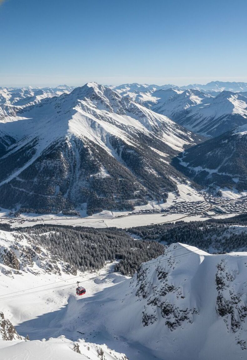 Panoramablick auf die verschneiten Garmischer Alpen mit roter Seilbahn und klarer Wintersonne – eindrucksvolle Kulisse für ein unvergessliches Firmenjubiläum in Garmisch.