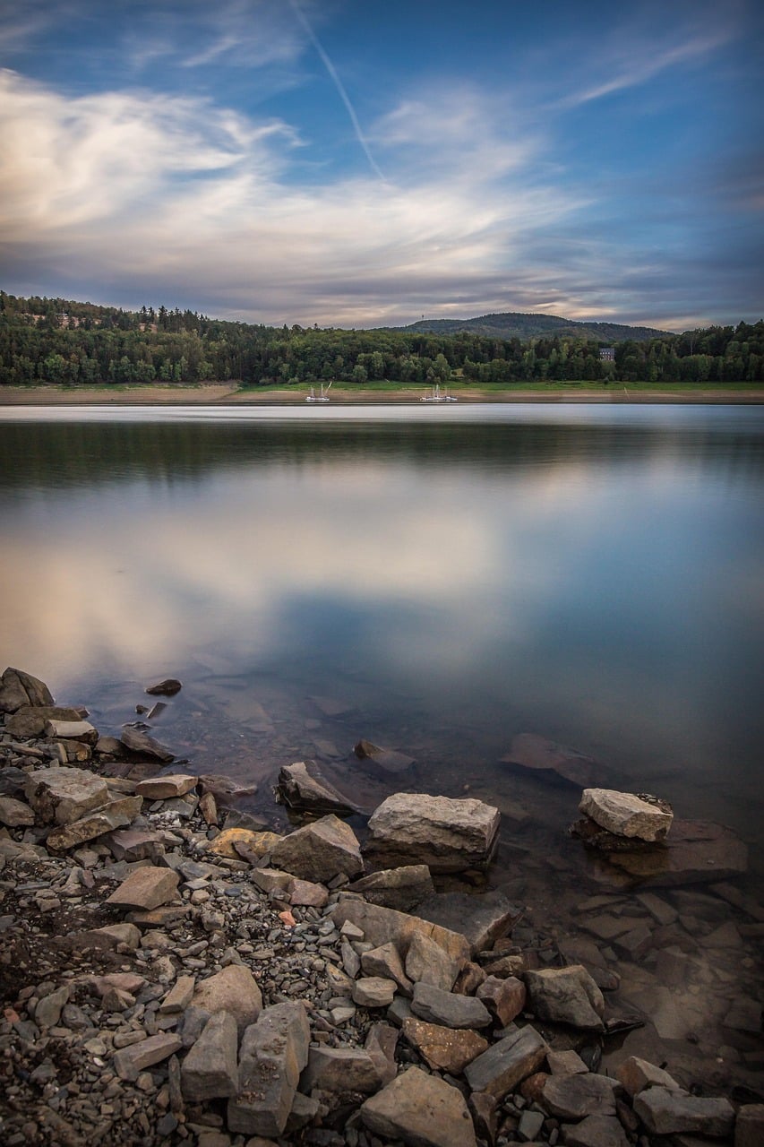 Teambuilding am Edersee: Ruhige Seelandschaft mit Blick auf bewaldete Hügel und steiniges Ufer – ideale Umgebung für entspannte Teamaktivitäten in der Natur