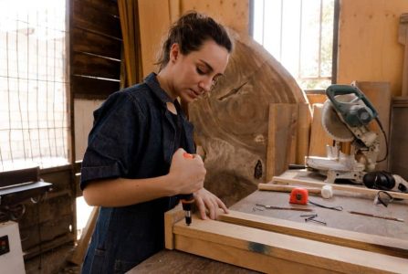 Frau bearbeitet Holz in einer Werkstatt